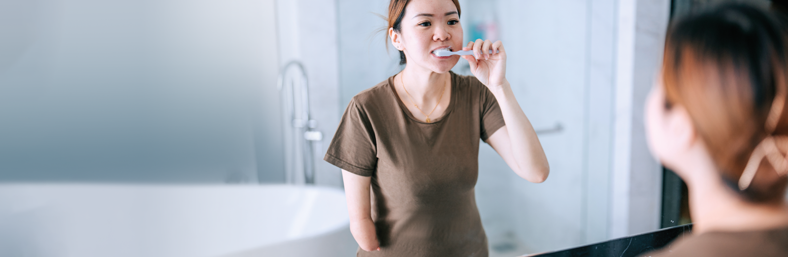woman-brushing-teeth-in-mirror-1600x522.png