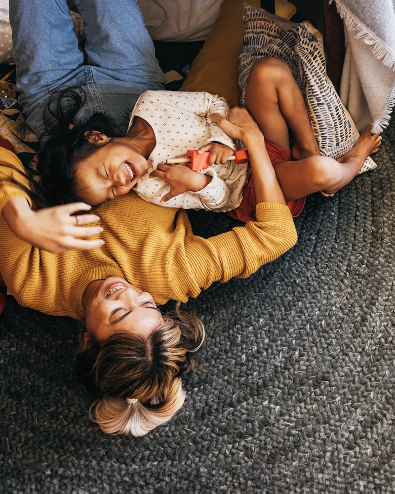 mom-and-daughter-laughing-on-the-floor-800x1000.webp